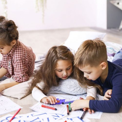 three-focused-children-are-playing-floor-drawing-coloring-books - Copy