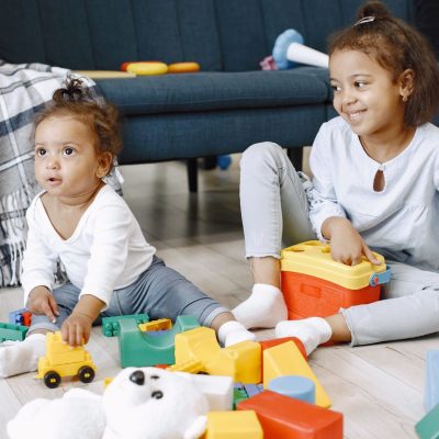 two-pretty-kids-sit-floor-play-with-toys-near-sofa-afro-american-sisters-playing-home